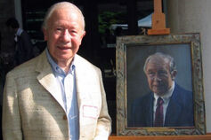 Karl F. Schuessler stands next to a painted portrait of himself.